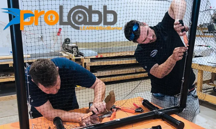 Two men assembling a netting frame at a training workshop.