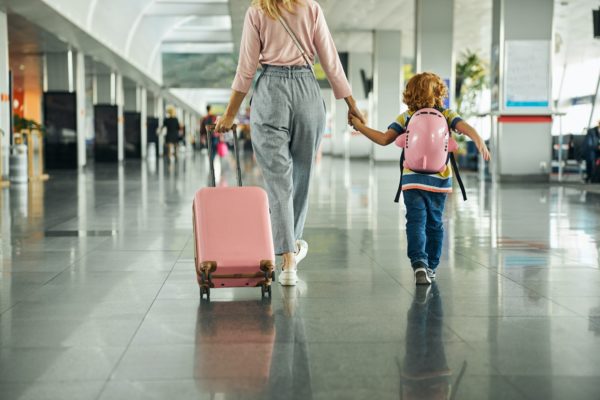 Woman guiding a kid through an airport hall