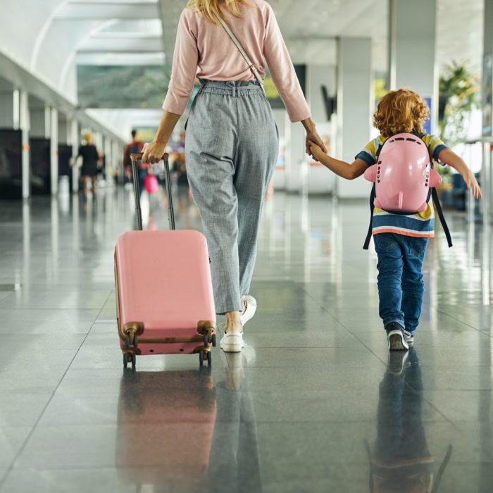 Woman guiding a kid through an airport hall